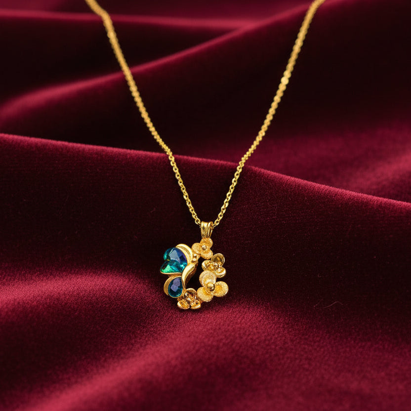 Gold necklace with a green gemstone on a white background